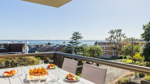 A balcony with a table set for breakfast, overlooking a cityscape and a body of water. - The Commodore 5, 9-11 Donald St - water views, air con, Wi-Fi (Nelson Bay)