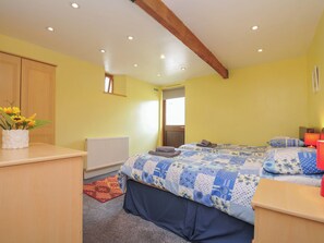 Ein Schlafzimmer mit Bett, Nachttisch, Heizkörper, Fenster und Tür.