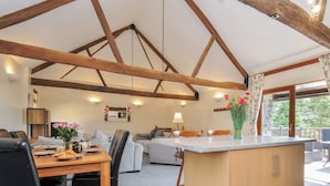 A spacious kitchen with a central island, wooden beams on the ceiling, and a view of the outdoors. - The Old Wagon House (Torpoint)