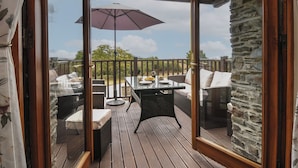 An outdoor deck with a table and chairs, a wooden ceiling, and a stone wall. - The Old Wagon House (Torpoint)