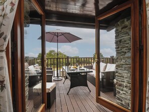 Eine Terrasse im Freien mit Tisch und Stühlen, einer Holzbalkendecke und einer Steinwand.