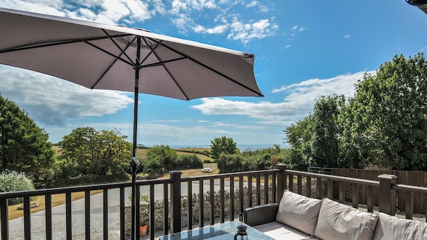 A patio with a table, outdoor seating, and a view of the landscape. - The Old Wagon House (Torpoint)
