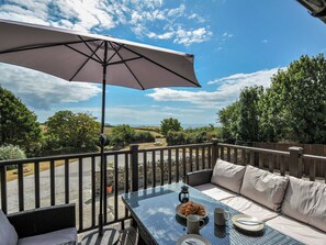 A patio with a table, outdoor seating, and a view of the landscape. - The Old Wagon House (Torpoint)