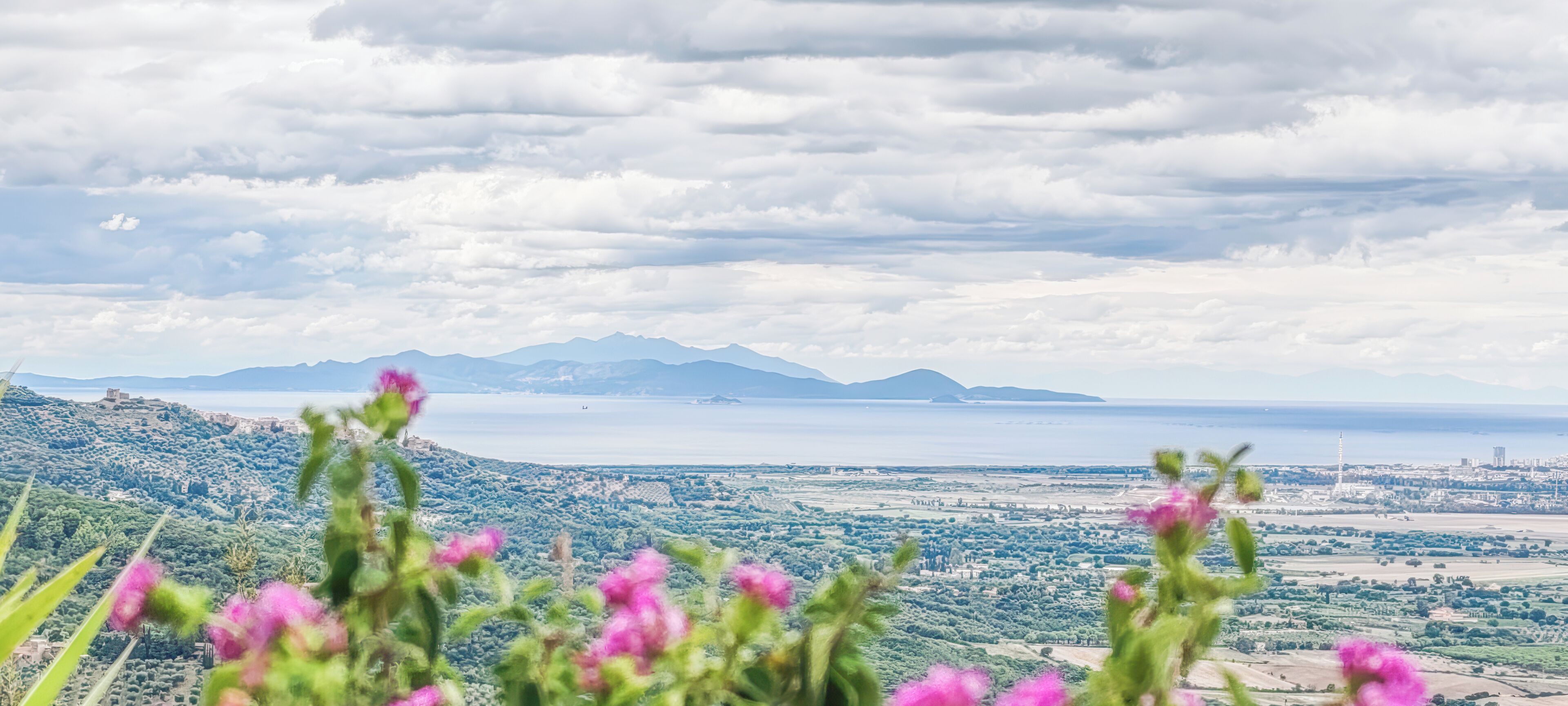 A landscape with mountains, a body of water, and a distant cityscape.