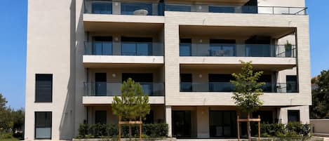 Un edificio de varios pisos con balcones, fachada de piedra y cielo despejado.