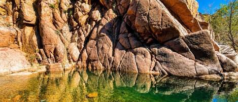 A natural rock formation with a clear reflection in a body of water.