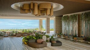 A modern lounge area with seating arrangements, a ceiling with hanging lamps, and a view of the outdoors. - Grand Fiesta Americana Riviera Cancún (Puerto Morelos)