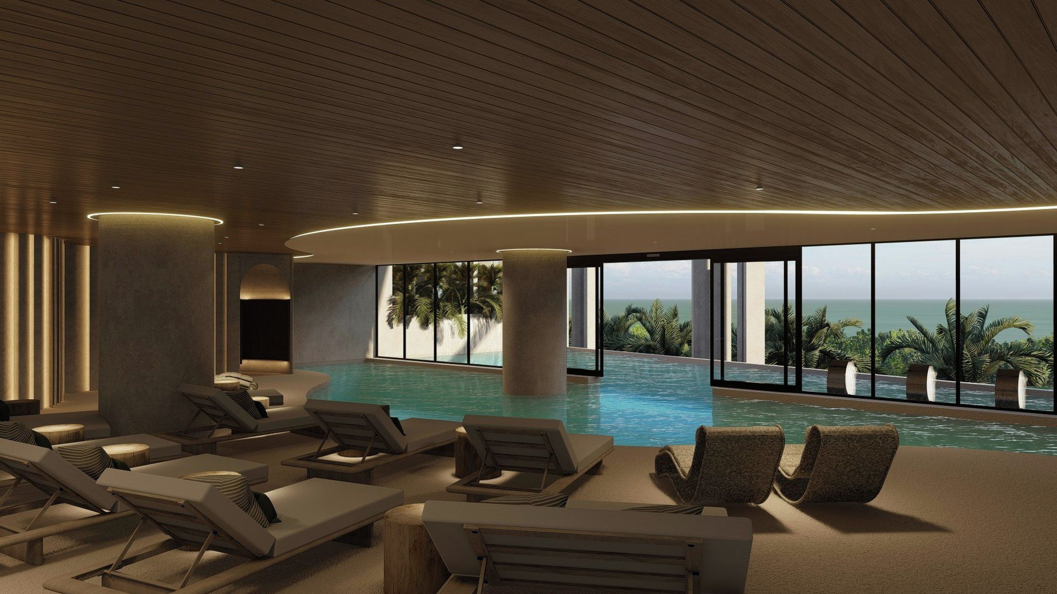 Una piscina interior moderna con sillones de descanso y amplios ventanales con vistas al océano.