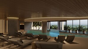 A modern indoor pool area with lounge chairs and a view of the ocean. - Grand Fiesta Americana Riviera Cancún (Puerto Morelos)