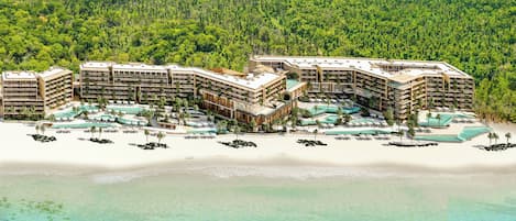A resort with multiple buildings, a beachfront, and a pool area.