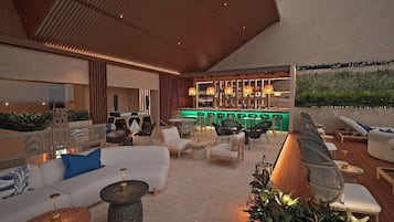 An outdoor lounge area with seating, a bar, and a view of greenery.