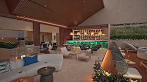 An outdoor lounge area with seating, a bar, and a view of greenery. - Grand Fiesta Americana Riviera Cancún All Inclusive (Puerto Morelos)