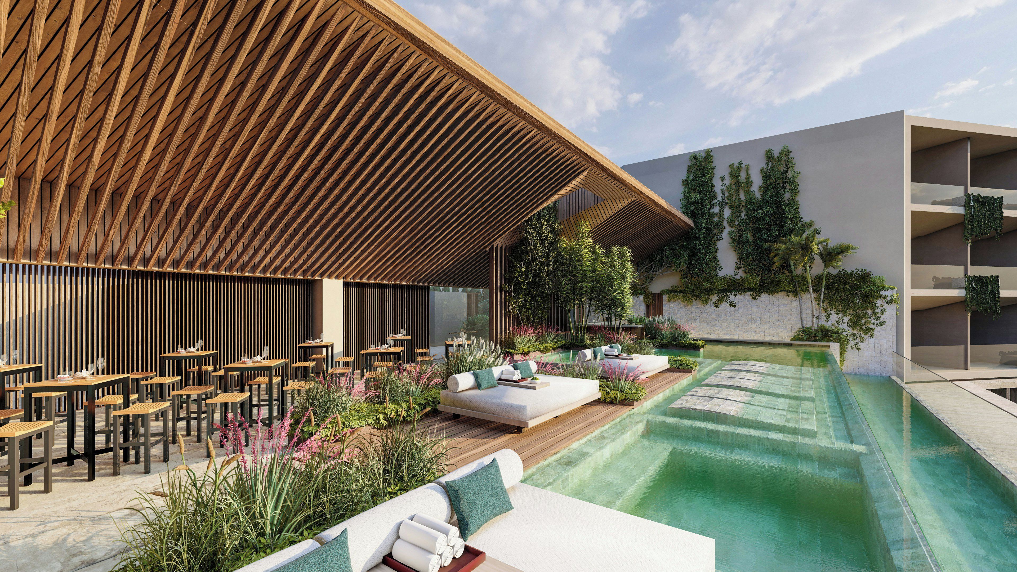 A modern outdoor seating area with wooden tables and chairs, a pool, and lush greenery.