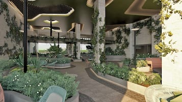 Un atrio interior con un espacio central abierto, rodeado de zonas de estar y follaje.