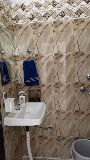 Ein Badezimmer mit Waschbecken, einem Spiegel, einem Handtuchhalter mit blauem Handtuch und einer Duschkabine.