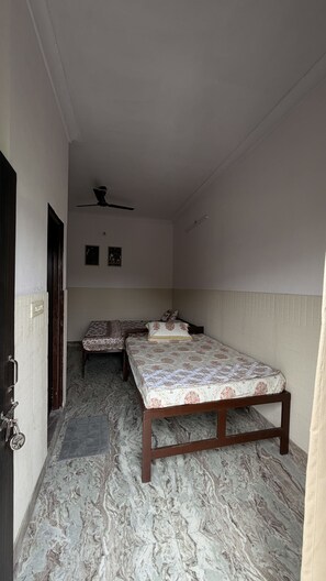 Ein Zimmer mit zwei Betten, einem Deckenventilator und einer Tür mit Schloss.