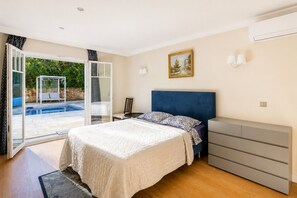 A bedroom with a bed, a dresser, a chair, and a painting on the wall. - Five-bedroom villa on Cap d'Antibes (Juan les Pins Antibes)