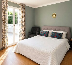 Un dormitorio con una cama grande, una silla y vistas al balcón.