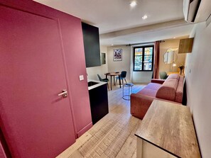A modern interior with a red door, a dining area with chairs and a table, and a sofa. - Cocon Bonaparte 2 - Garibaldi (Nice)