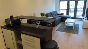 Un espacio moderno para vivir con kitchenette, un sofá, una mesa de centro y un televisor.