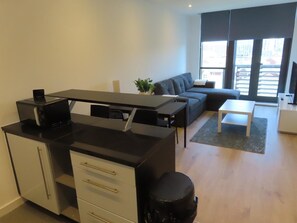 Ein modernes Wohnzimmer mit Küchenzeile, einer Couch, einem Couchtisch und einem Fernseher.