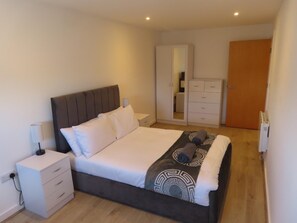 Un dormitorio con cama, mesitas de noche, armario y espejo.