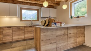 A modern kitchen with wooden cabinetry, a central island, and pendant lighting. - Chalet Elsa - renovated 4 bedroom chalet with a Jacuzzi & sauna in les Houches (Les Houches)