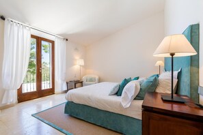 Ein Schlafzimmer mit Bett, Nachttischen, einem Sessel und einer Lampe.