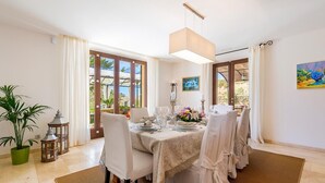 A dining area with a table set for four, a potted plant, and a painting on the wall. - Son Polvell, Finca 5StarsHome Mallorca (Andratx)