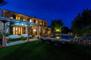 Une maison à deux étages dotée d’une piscine, d’un espace salon extérieur et d’un patio couvert.