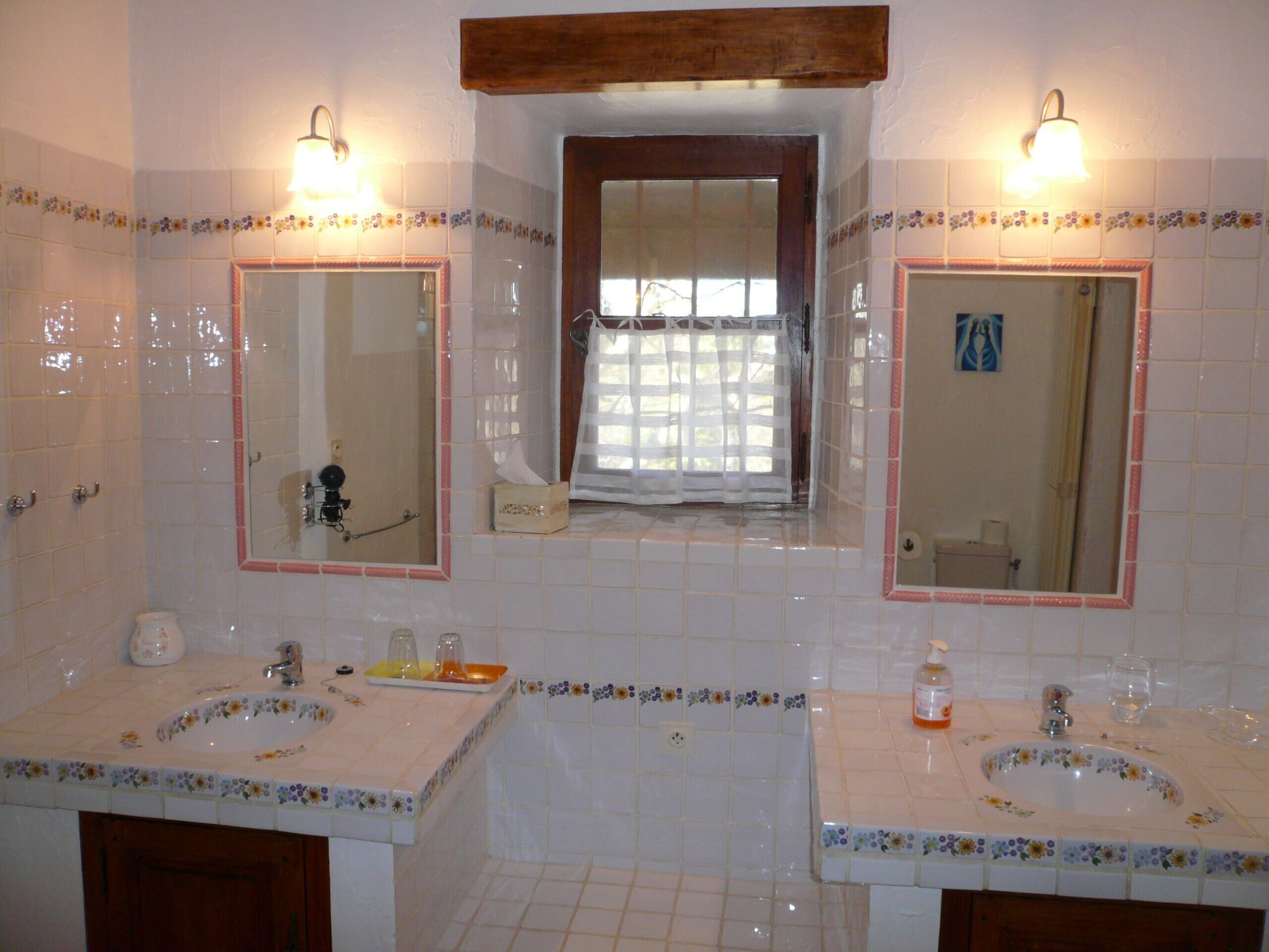 Casa de banho com duas pias, um espelho e uma janela.