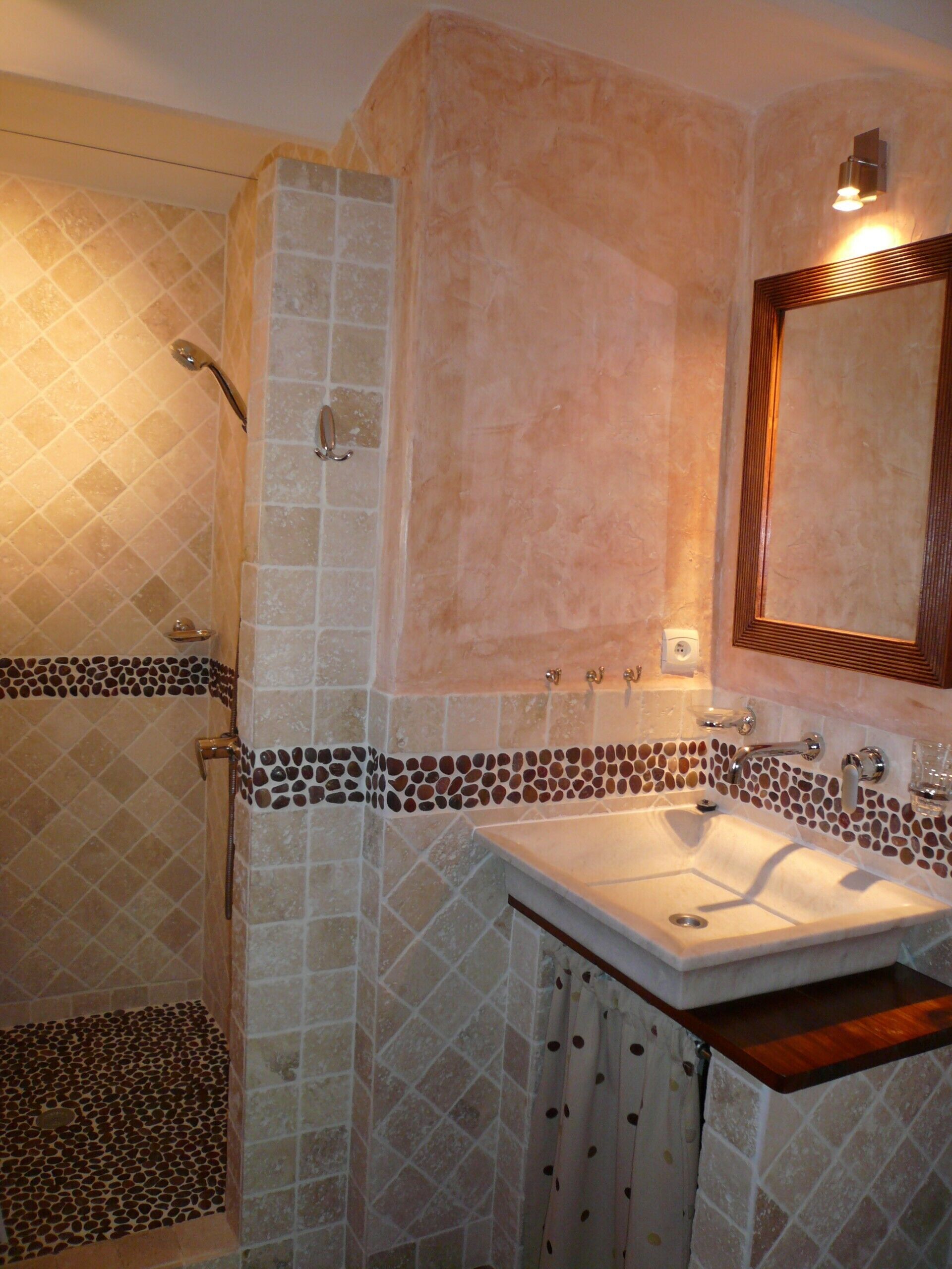 Une salle de bain avec une douche, un lavabo et un miroir.