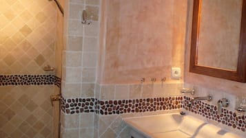 Une salle de bain avec une douche, un lavabo et un miroir.