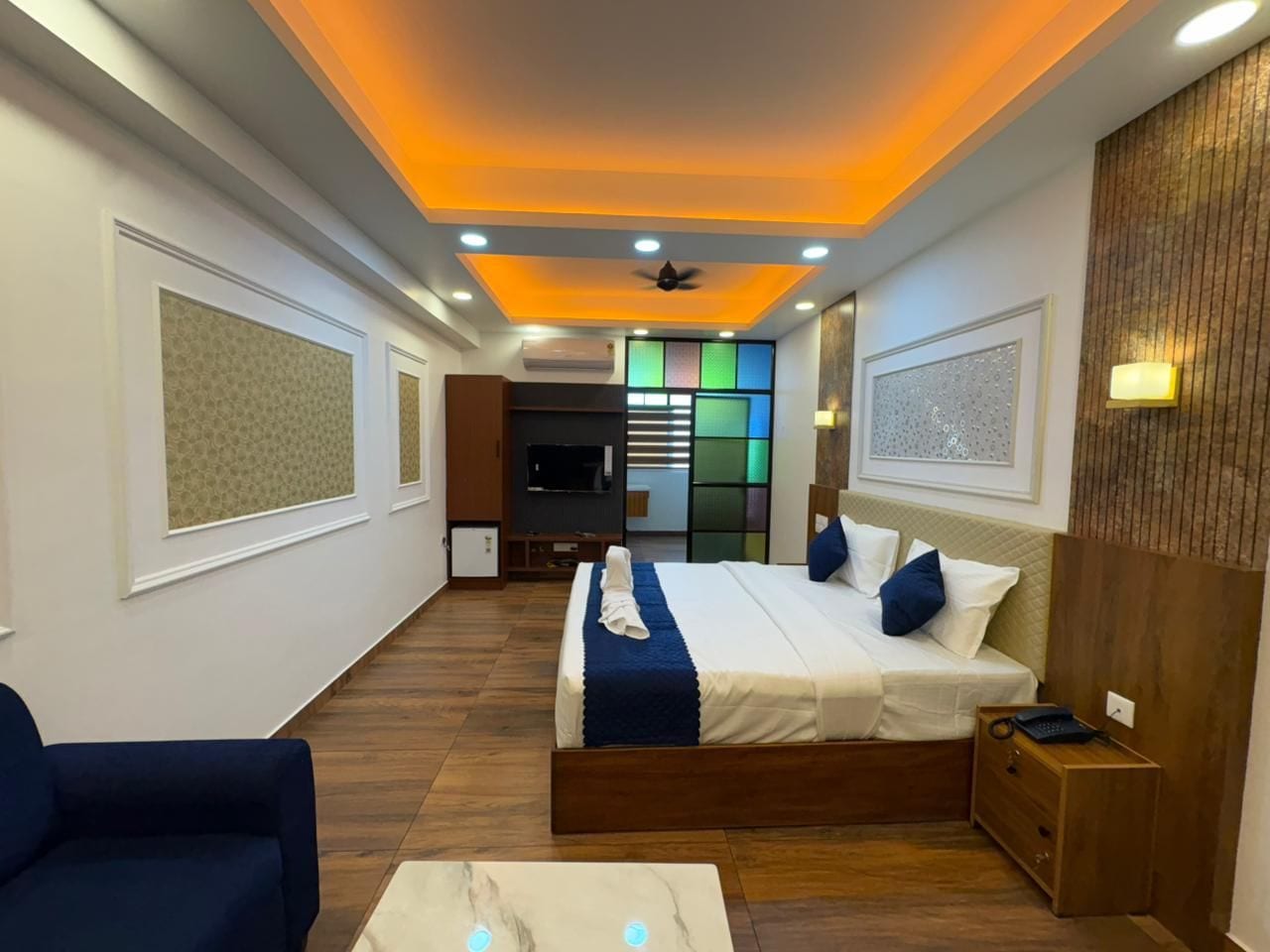 A modern hotel room with a large bed, a desk, and a seating area.