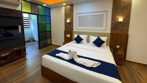 A hotel room with a bed, a television, and a wooden floor. - Odyssey Rendezvous (Kunnathunad)