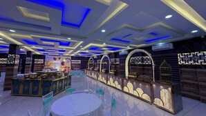 A banquet hall with a central round table, decorative arches, and a bar area with a lighted display. - Odyssey Rendezvous (Kunnathunad)