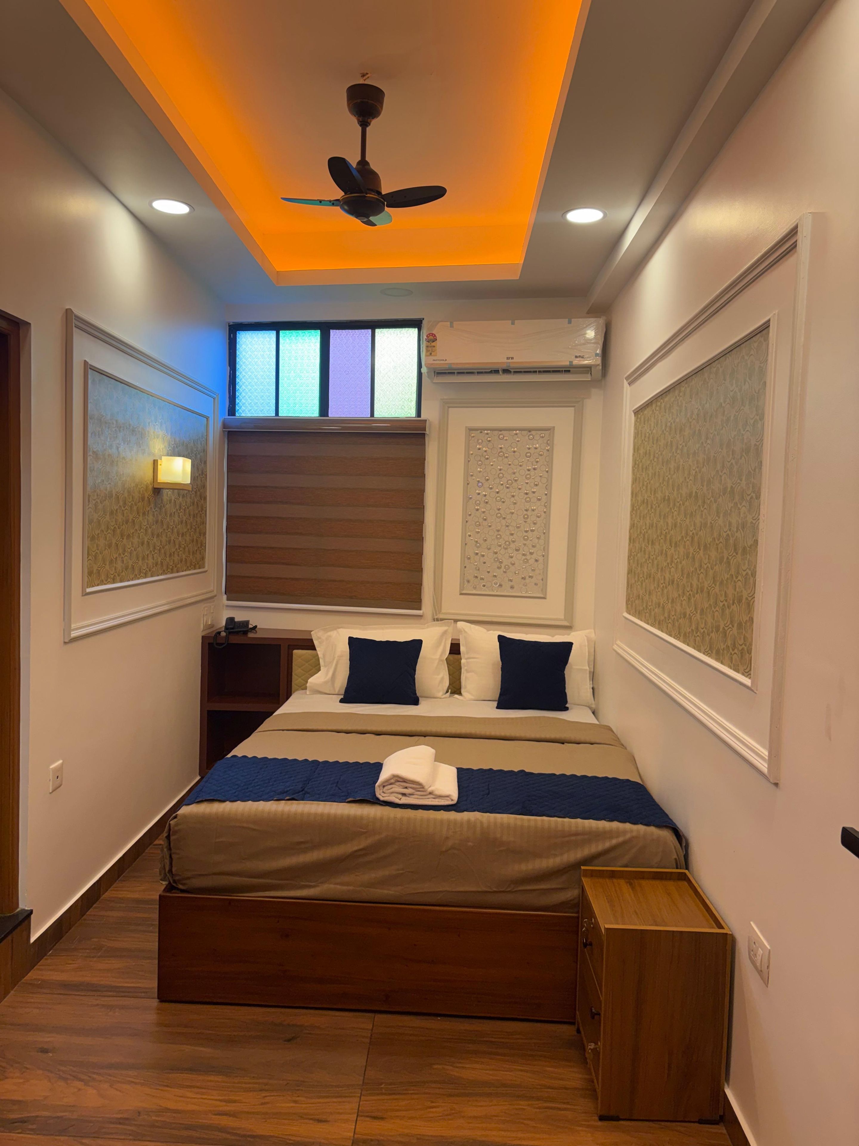 Quarto de hotel com cama, mesa de cabeceira e ventilador de teto.