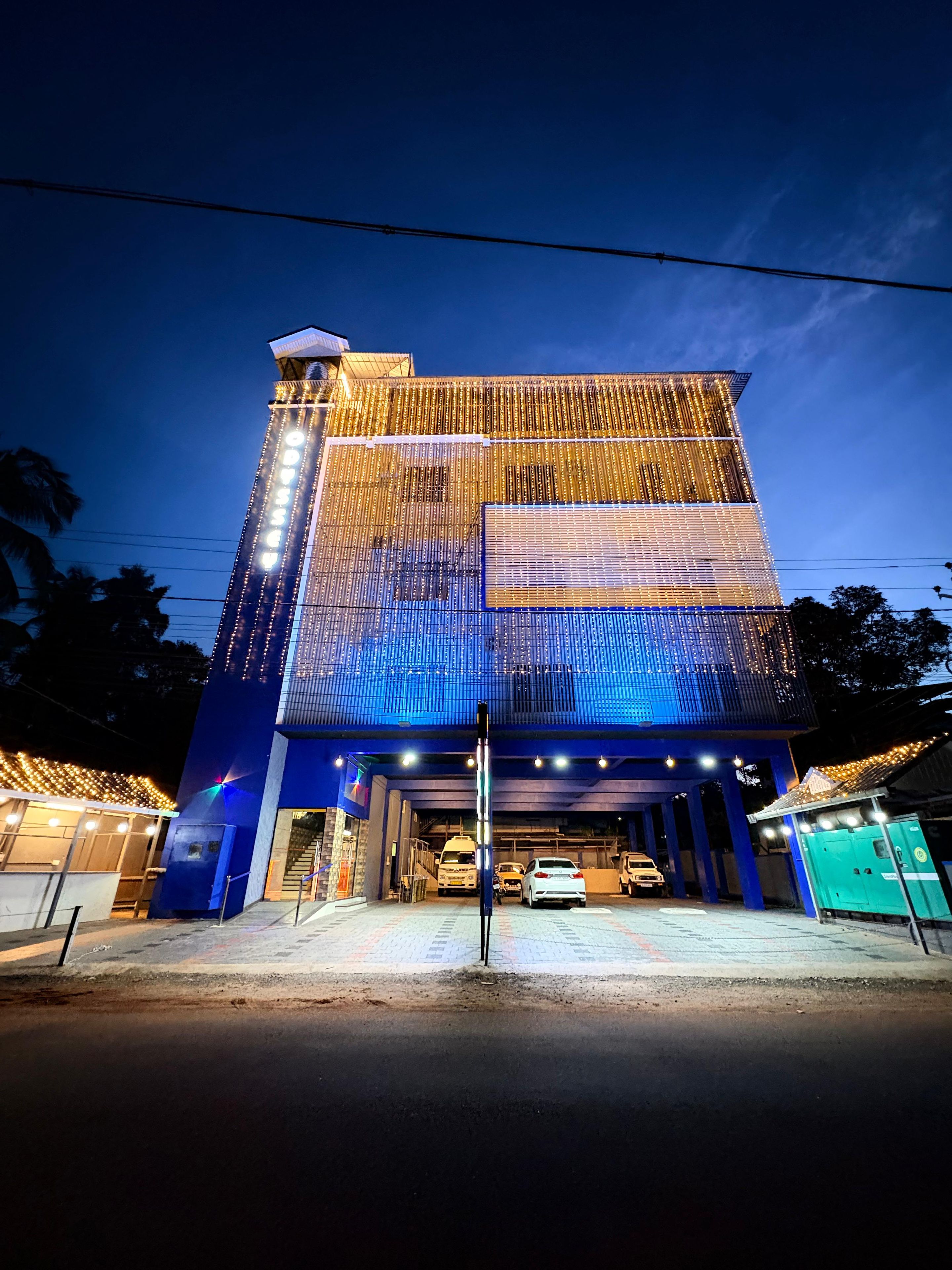 Un edificio de varios pisos con una entrada destacada y un área techada para vehículos.