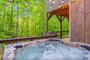 Ein Whirlpool, umgeben von einer Holzterrasse mit Blick auf einen Wald.