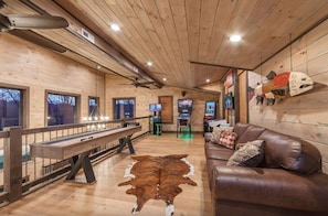 Een houten interieur met een pooltafel, een leren bank en een groot vloerkleed.