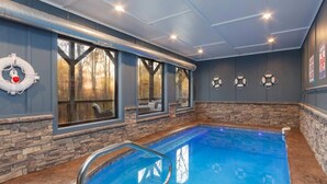 En indendørs swimmingpool med stenvægge og store vinduer.