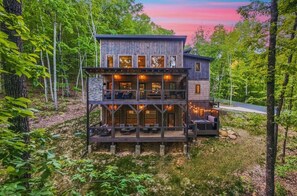 Eine zweistöckige Holzhütte mit Balkon, umgeben von Bäumen.
