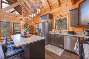 A kitchen with a granite countertop, stainless steel appliances, and wooden cabinetry. - PeacefulCreek: Pool, HotTub, Wifi, FirePit, Pets, Creek, Resort Facilities (Sevierville)