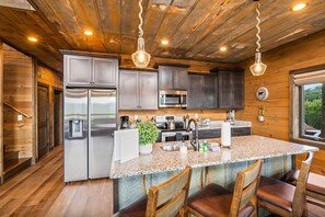 A kitchen with stainless steel appliances, granite countertops, and wooden cabinetry. - SerenityLod: POOL, Theater, Games, HotTub, Wi-Fi, Pets (Sevierville)
