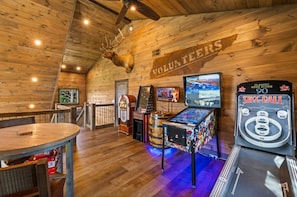 A room with wooden walls, a mounted deer head, a dartboard, and a pinball machine. - SerenityLod: POOL, Theater, Games, HotTub, Wi-Fi, Pets (Sevierville)