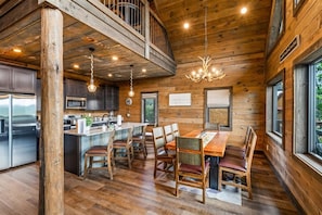 A wooden interior with a dining area, kitchen, and a balcony. - SerenityLod: POOL, Theater, Games, HotTub, Wi-Fi, Pets (Sevierville)