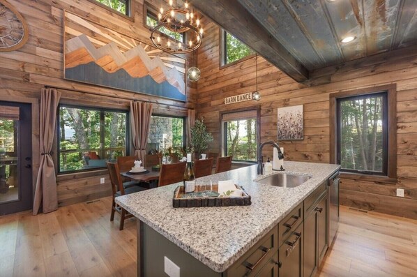 Un intérieur en bois avec un îlot de cuisine, un coin repas et de grandes fenêtres.