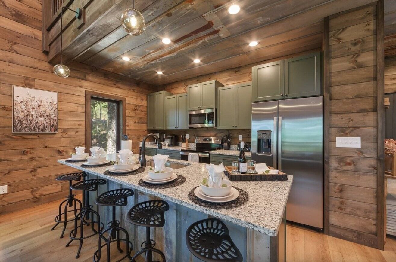 A kitchen with wooden walls, a granite countertop, stainless steel appliances, and bar stools.