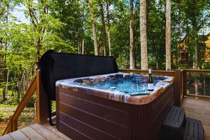 Ein Whirlpool auf einer Holzterrasse, umgeben von Bäumen.
