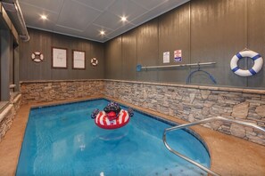Ein Hallenbad mit einem Rettungsboje, einem Sprungverbotsschild und gerahmten, motivierenden Sprüchen an der Wand.